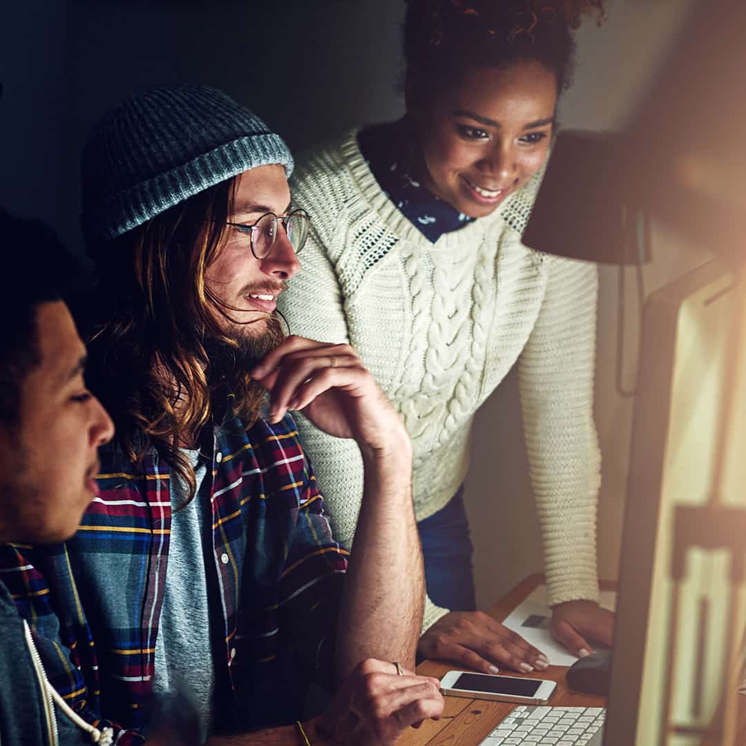 Three creative professionals collaborating at a computer